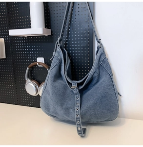 Detail of large denim tote bag featuring metal eyelet straps on a display board