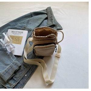 Détail d'un sac bandoulière en nylon beige imperméable avec cordon et poche zippée