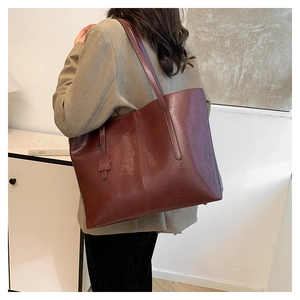 Model wearing a large burgundy tote bag in premium faux leather with vertical stitching