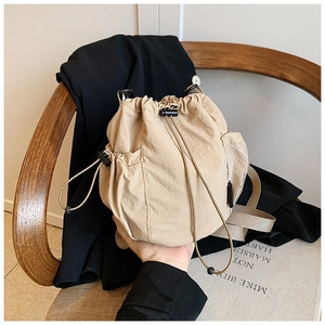 Detail of beige nylon drawstring bucket bag with mesh side pocket and adjustable cord
