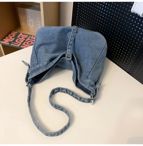 Detailed close-up of blue denim hobo bag featuring silver metal eyelet grommet decorations