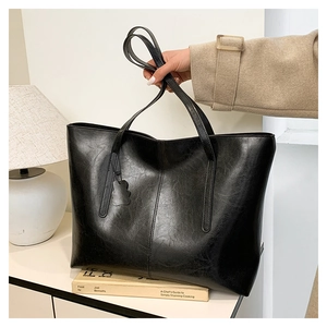 Detail of black faux leather tote bag with vintage texture and rabbit charm accessory