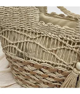 Detalle del bolso tote bohemio de paja con tejido calado y borlas decorativas