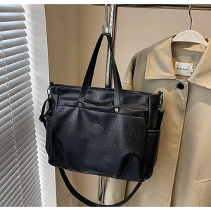 Gros plan du sac cabas en cuir noir texturé avec poche avant magnétique et rivets décoratifs