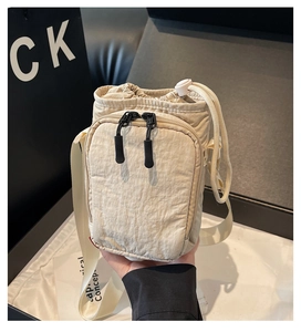 Vue détaillée du sac bandoulière en nylon beige avec poche avant à double zip