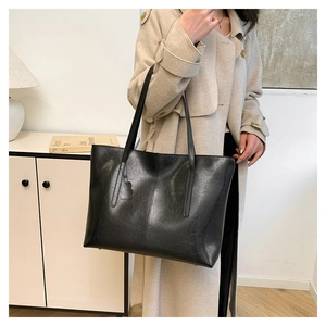Large black vintage tote bag shown on model wearing a trench coat for work style