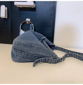 Detailed close-up of blue washed denim tote bag with metallic eyelets and strap buckles