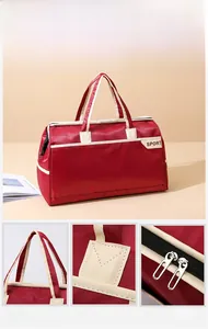 Detail view of red travel bag showing reinforced stitching and two-way hardware zippers