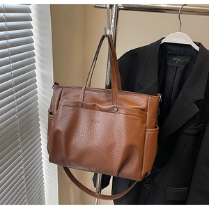 Détail du sac cabas marron à motif litchi avec poche avant et rivets métalliques