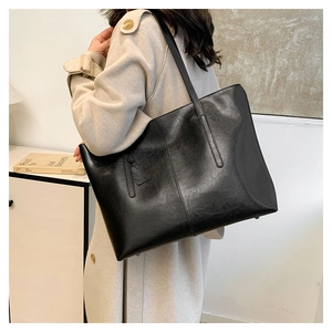 Close-up of black leather tote bag featuring detailed vertical stitching and shoulder strap