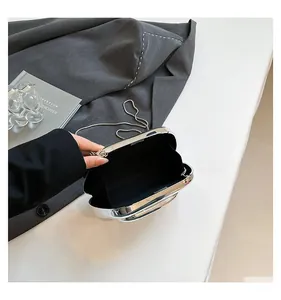 Detailed view of silver metallic evening clutch open showing black fabric lining and chain