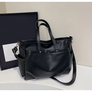 Détail du sac cabas noir à texture grainée avec boucles argentées et poches latérales