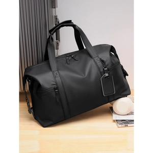 Large black waterproof travel duffel bag with leather luggage tag on a silver suitcase