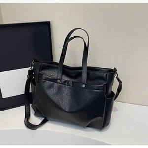 Détail d'un sac cabas noir avec texture cuir litchi et poches à rivets métalliques