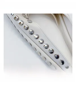 Detailansicht der weißen Ledertasche mit dekorativen silbernen Metallnieten und Nähten