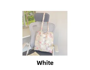 Dettaglio della borsa tote in tela con stampa floreale colorata ed etichetta del marchio