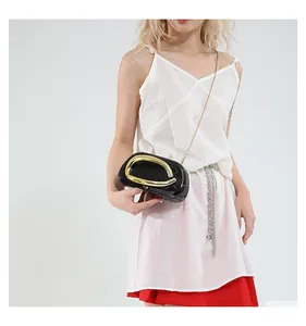 Detail of black patent leather evening bag with large gold circular metal handle and chain