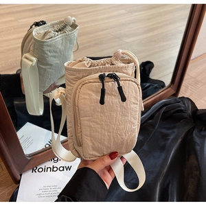 Détail du sac bandoulière en nylon beige avec cordon de serrage et poche zippée avant