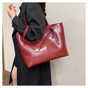 Macro shot of deep burgundy tote bag showcasing shiny oil wax leather texture and stitching