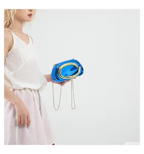 Detail of blue metallic evening clutch bag with golden chain and letter handle