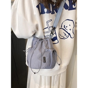 Light purple drawstring crossbody bucket bag with adjustable wide strap and side pockets