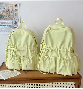 Detail of light green bow backpacks in two sizes with drawstring pockets and matte finish