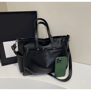 Détail d'un sac cabas en cuir grainé noir avec poches latérales et bandoulière amovible