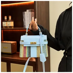 Dettaglio borsa in pelle blu e rafia intrecciata con chiusura oro su scaffale