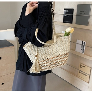 Detalle de bolso tote de paja boho con flecos de borlas y cuentas de madera en la bandolera