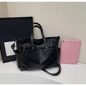 Détail du cabas en cuir grainé noir avec poche à boucle et poches latérales
