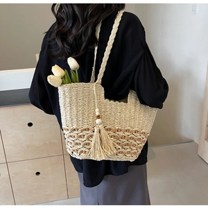 Primer plano del bolso de playa tejido beige con borla y textura detallada de paja