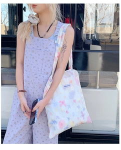 Dettaglio della borsa tote in tela bianca a fiori con etichetta e pantaloni coordinati