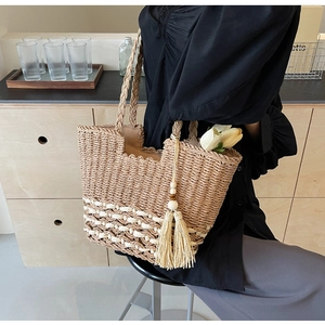 Detalle del bolso de paja tejida con asas de cuerda trenzada y adorno de borla decorativa