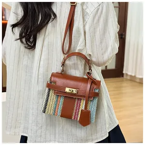 Dettaglio borsa di paglia a righe colorate con patta in pelle marrone e chiusura dorata