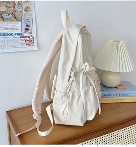 Close-up of cream white backpack with side bow drawstring and breathable mesh straps