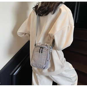 Détail d'un petit sac de téléphone en nylon gris clair avec cordon de serrage sur modèle