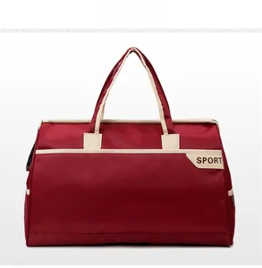 Front view of large red travel bag with SPORT lettering and cream webbing handles