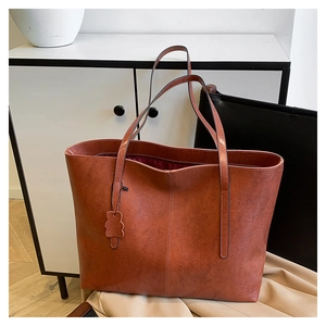 Detail of rust red tote bag featuring lychee texture leather and cute bear charm pendant