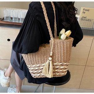 Detalle del bolso tote de paja tejida con correas largas y decoración de borlas