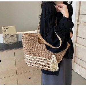Detalle de bolso tote bohemio tejido con patrones blancos y borla de cuentas de madera