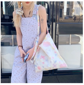 Dettaglio della borsa tote floreale e della salopette lavanda indossata dalla modella