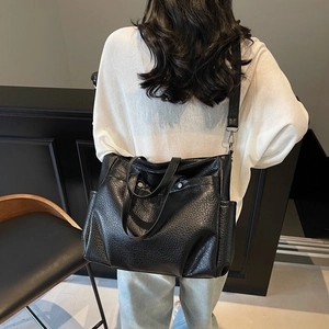 Grand sac cabas en cuir grainé noir avec doubles poignées porté par un mannequin chic