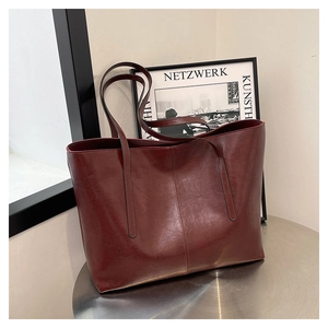 Detail of burgundy vintage tote bag with fine oil-wax texture and double shoulder straps