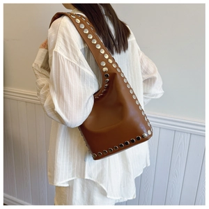 Detail einer braunen Vintage-Ledertasche mit großen Silbernieten am Schultergurt