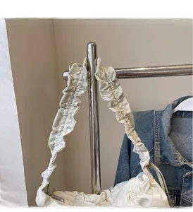 Dettaglio di un manico arricciato bianco crema su una borsa in pelle opaca con pieghe
