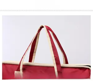 Detailed view of beige handles and precise stitching on the red travel bag