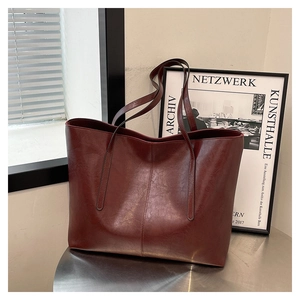 Detail of vintage deep burgundy tote bag with pebble leather texture on a metal table