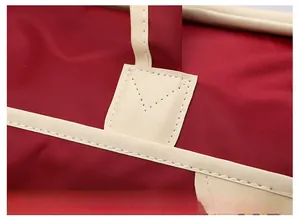 Detailed macro view of reinforced white stitching on burgundy travel bag leather handle