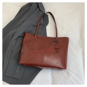 Close-up of vintage burgundy tote bag with leather texture, floral charm and metal studs