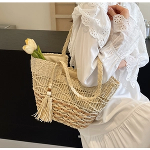 Detalle de bolso tote bohemio de paja con tejido calado y elegantes borlas decorativas